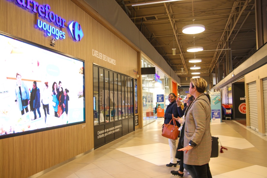 Vitrine interactive Carrefour Voyages — spectateurs captivés par la façade LED